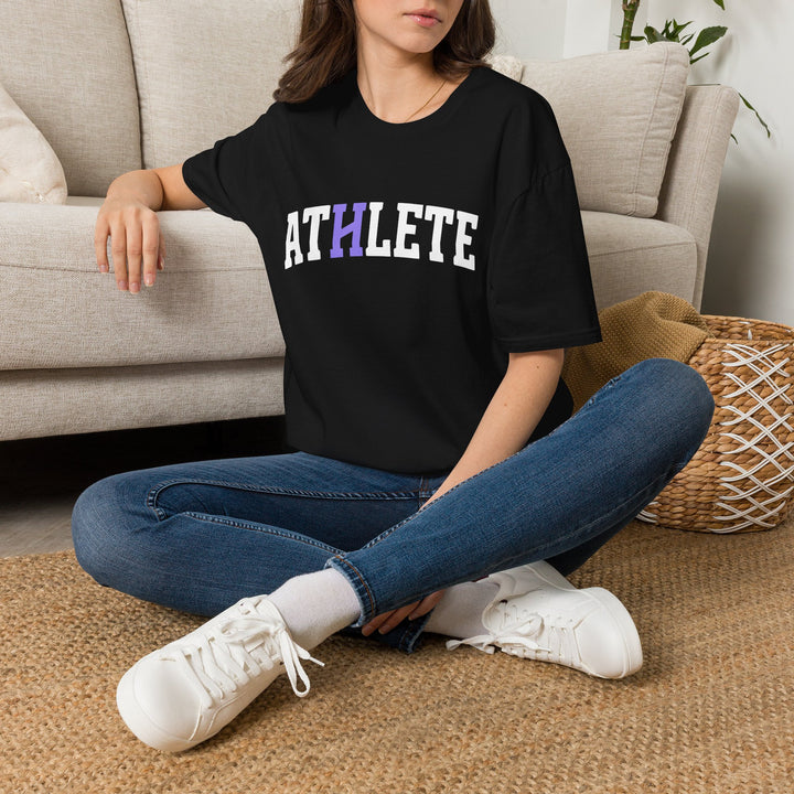 Person wearing a black t-shirt with text sitting on the floor in a living room.