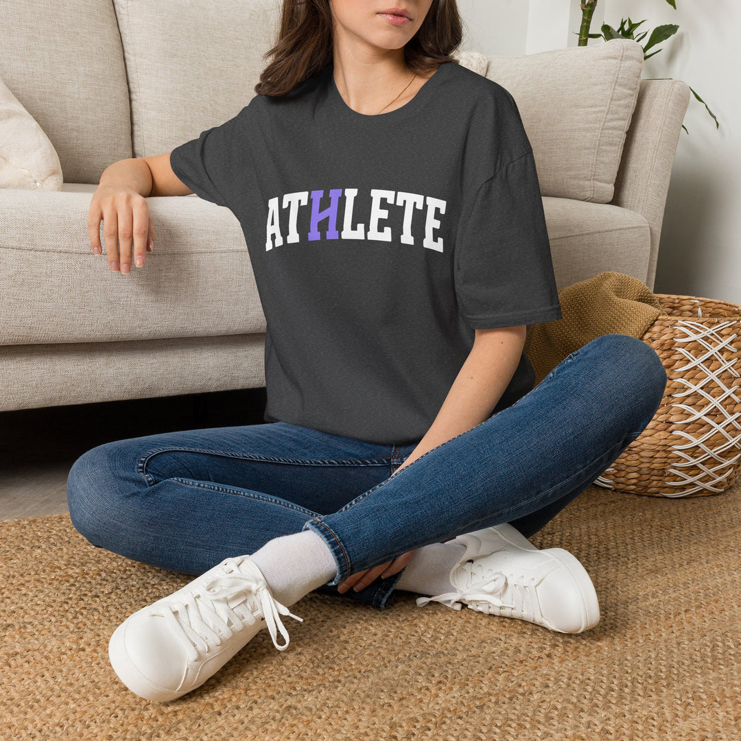Person wearing a dark gray t-shirt with a graphic design, sitting on the floor in a living room.