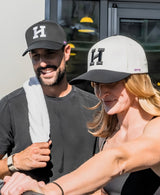 Two people wearing Hype's The Daily cap outdoors, one holding a towel.